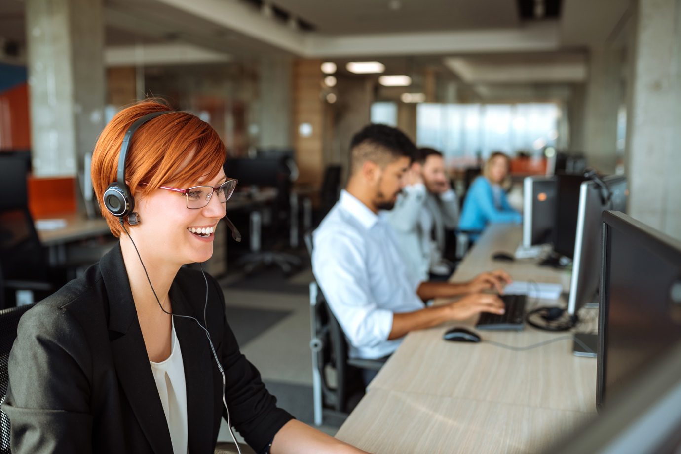 smiling girl with headset working at computer in office