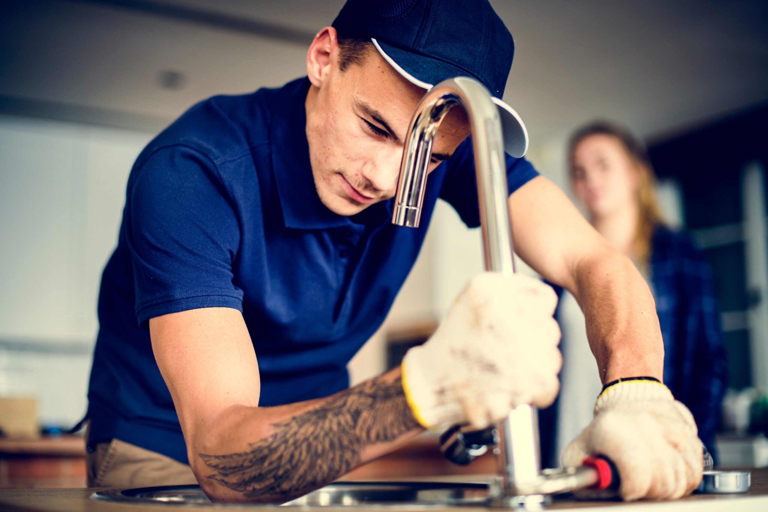 Plumber fixing kitchen sink to help customer